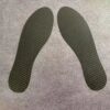 A close-up image of carbon fibre insoles next to a pair of sports shoes.